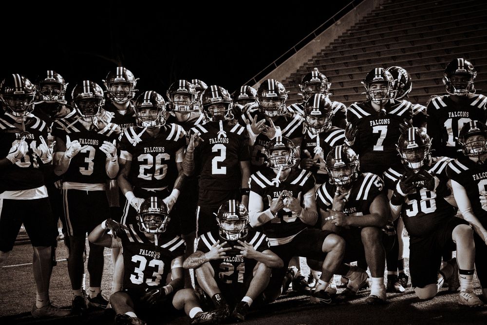 Football players in black and white uniforms engage in a pre-game huddle on the field.