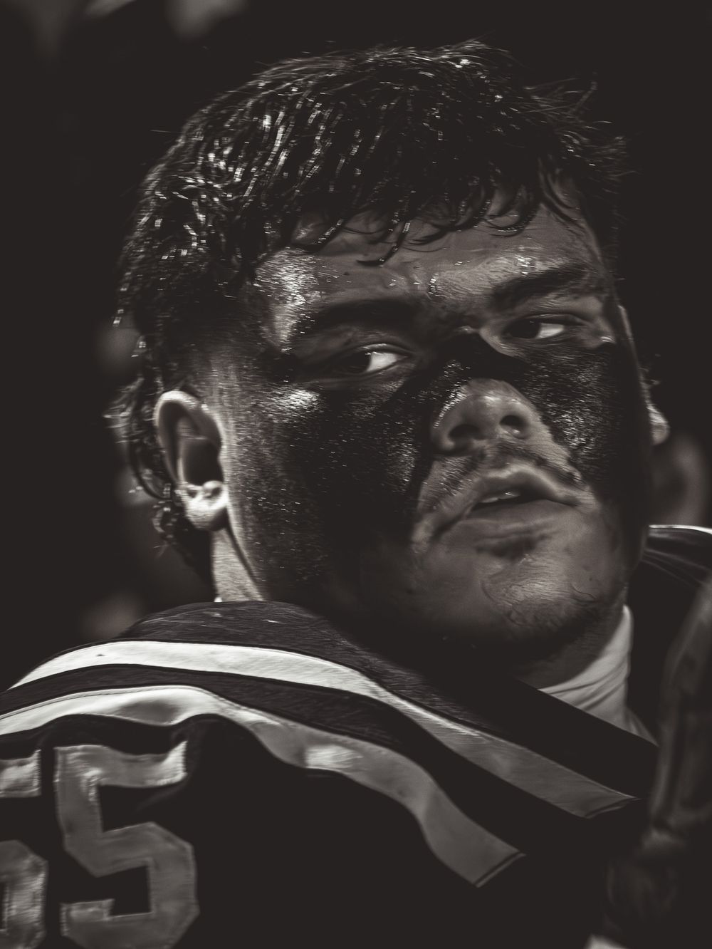 Dark dramatic close-up shots of football players wearing helmets during a game.