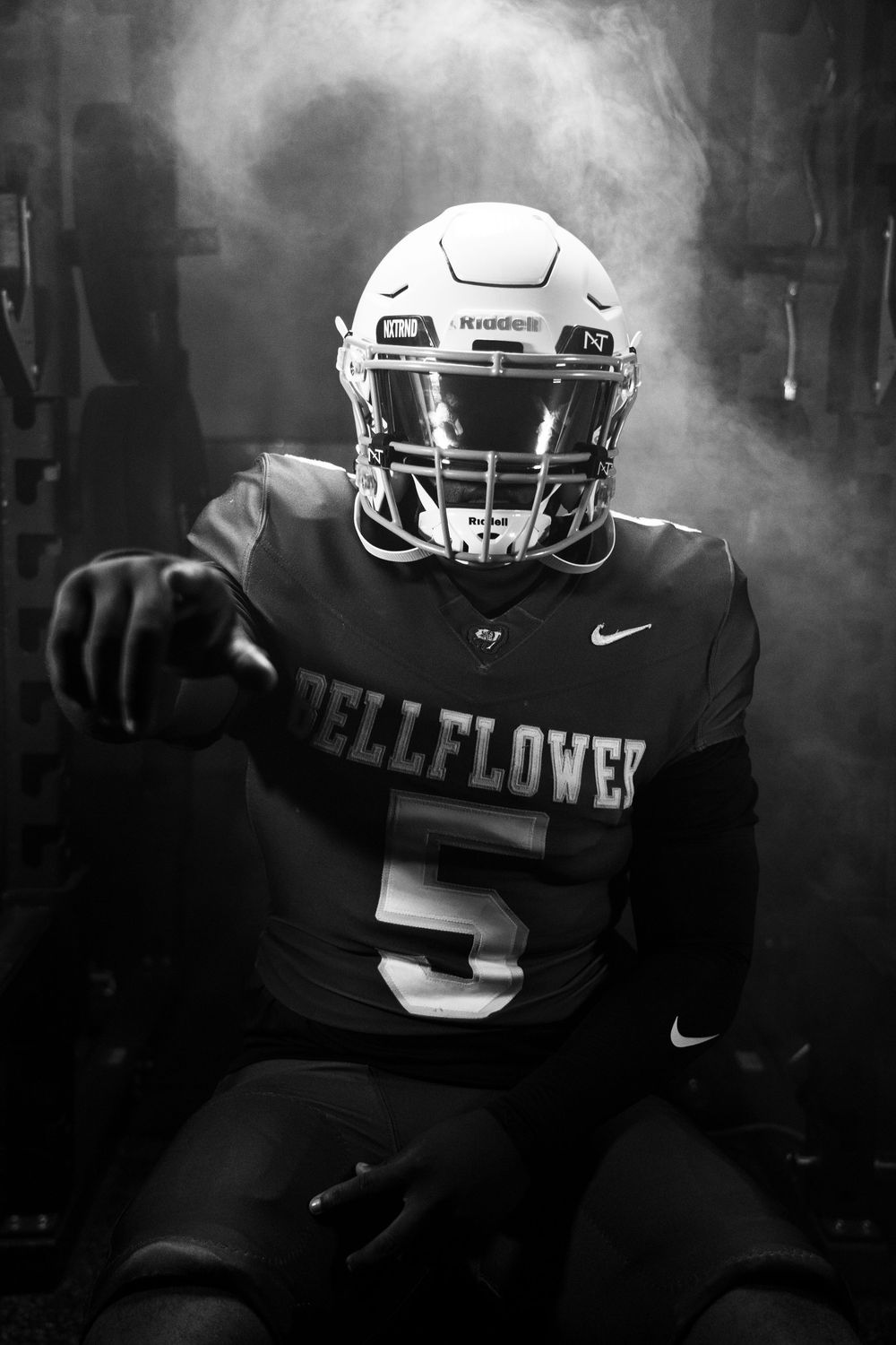Dramatic black and white portrait of Bellflower football player in uniform and helmet.