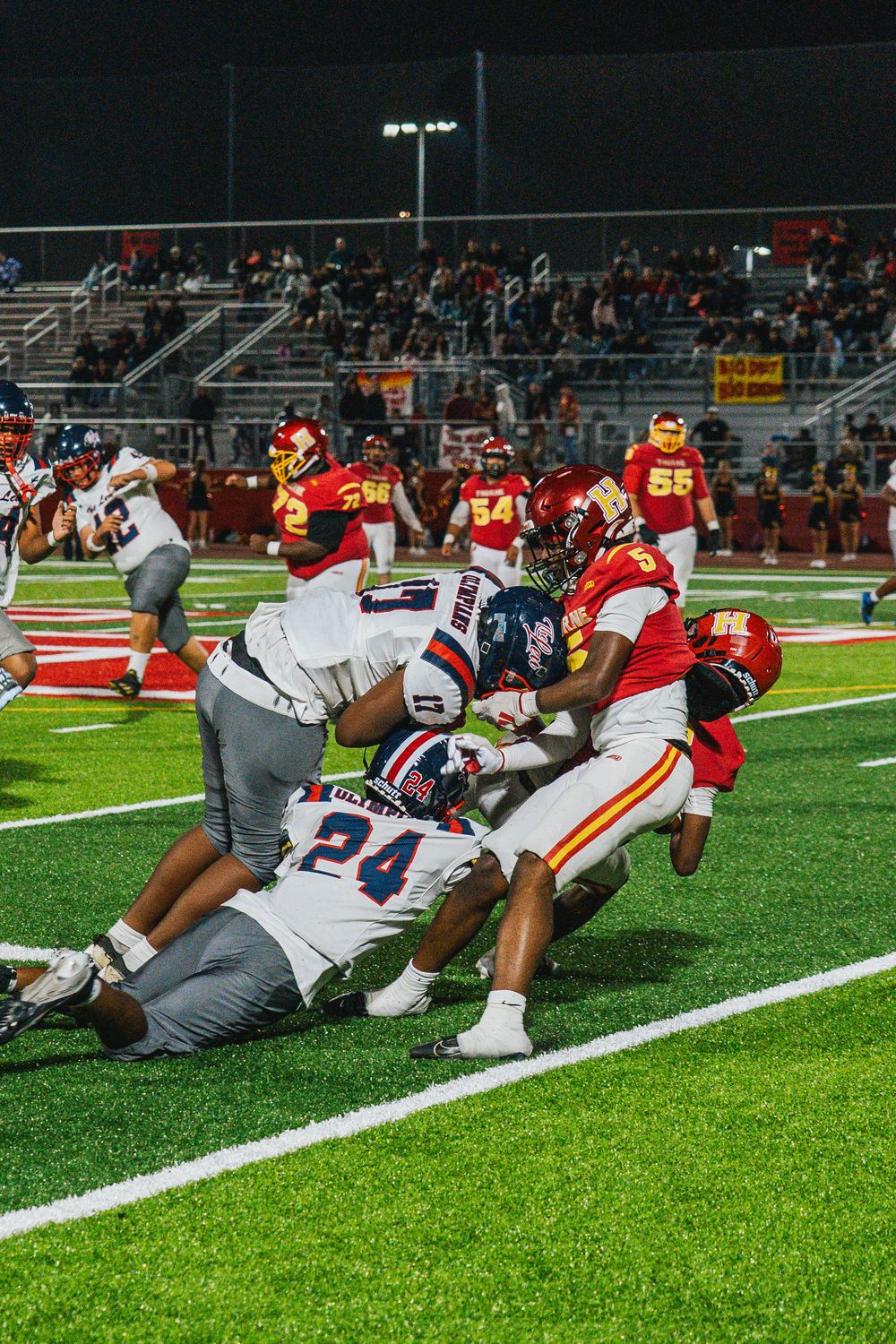 Football players perform stretching exercises on the field during a pre-game warmup session.