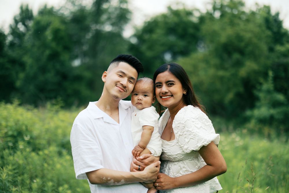 Family shares joyful moments together in an outdoor photoshoot with greenery in the background.