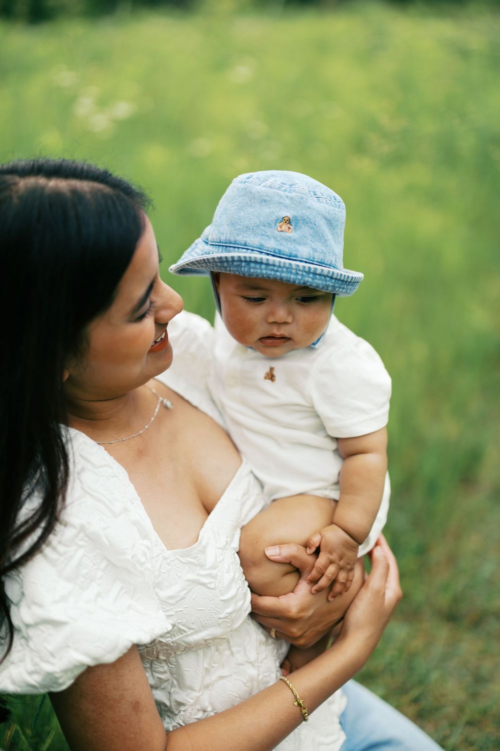 A series of outdoor portraits showing tender moments between a parent and young child in the green grass.