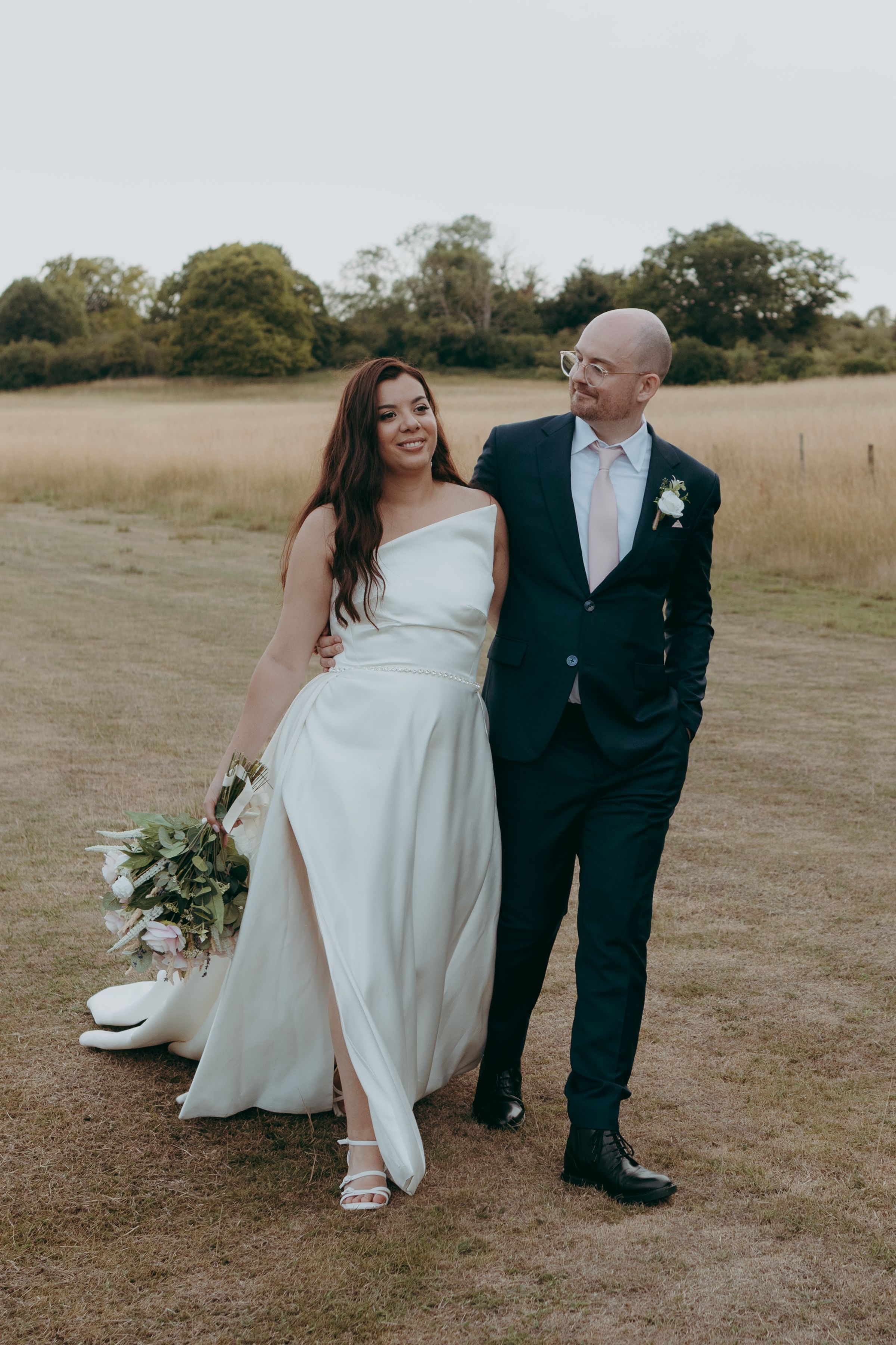 A series of candid wedding photos showing a couple sitting together in a sunlit grassy field.