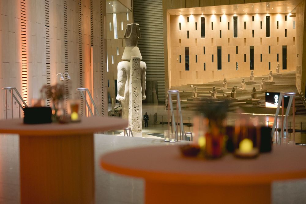 Elegant dining room setup with round wooden tables and modern lighting fixtures on the wall.