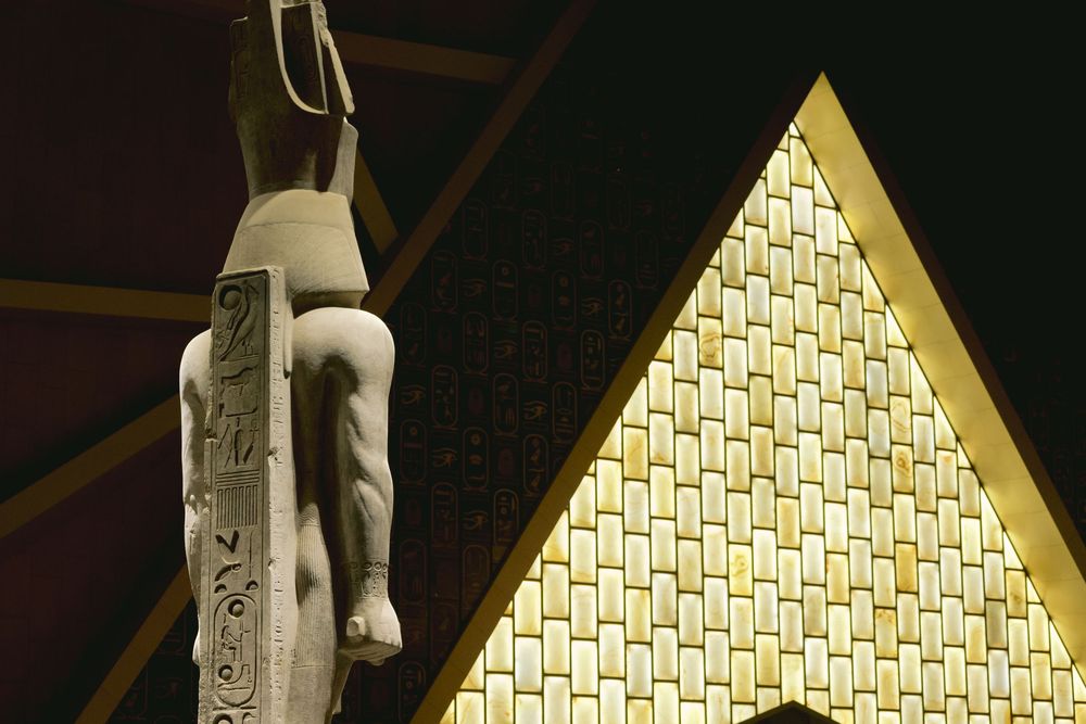 Illuminated modern church interior featuring a geometric golden pyramid pattern and architectural column detail.