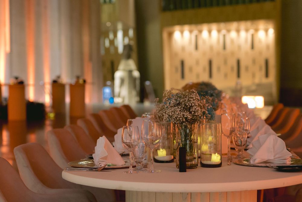 Elegant round banquet table with romantic candlelight centerpiece and folded napkins in warm ambient lighting.