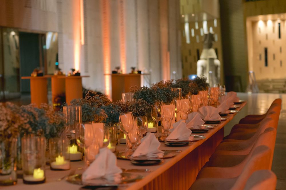 Long banquet table set with pink napkins and glowing candles creating an intimate wedding reception atmosphere.