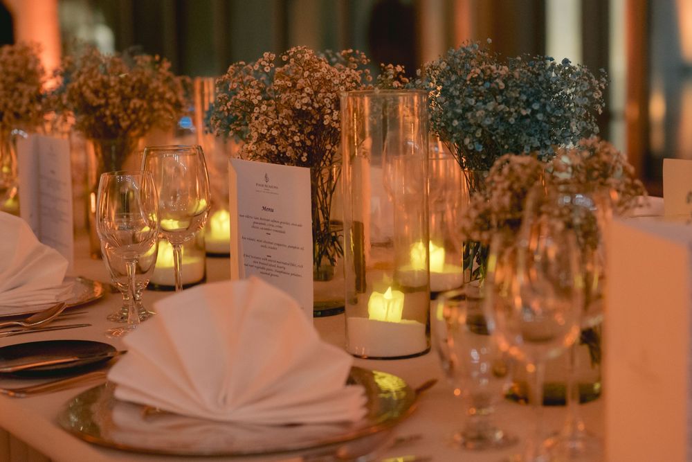 Elegant wedding reception table setting with candlelit centerpieces, folded napkins and delicate floral arrangements.
