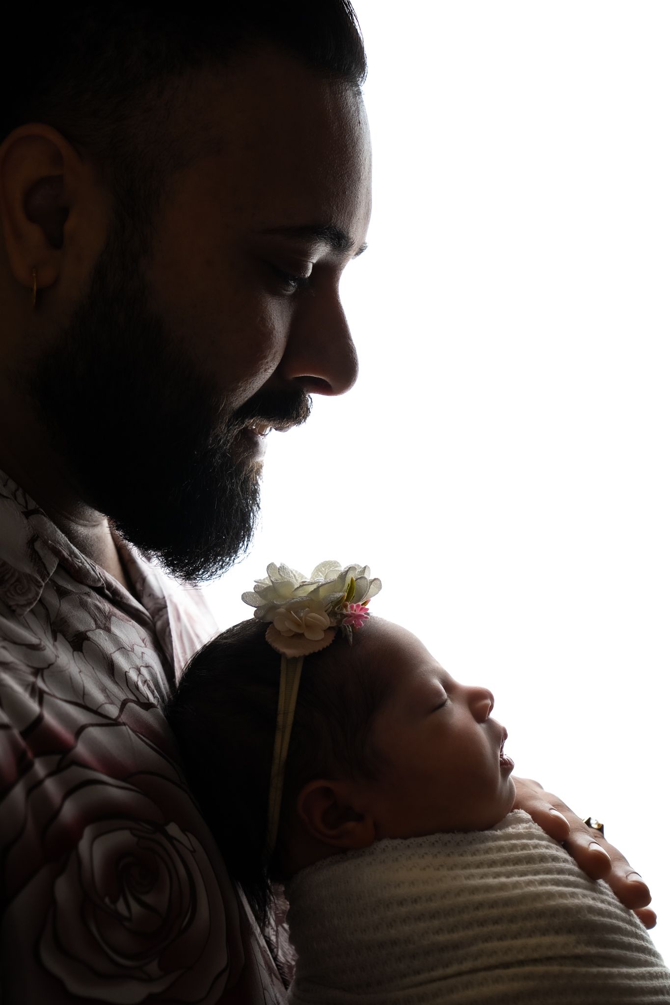 Silhouette of person holding sleeping baby in tender moment with soft backlit glow.