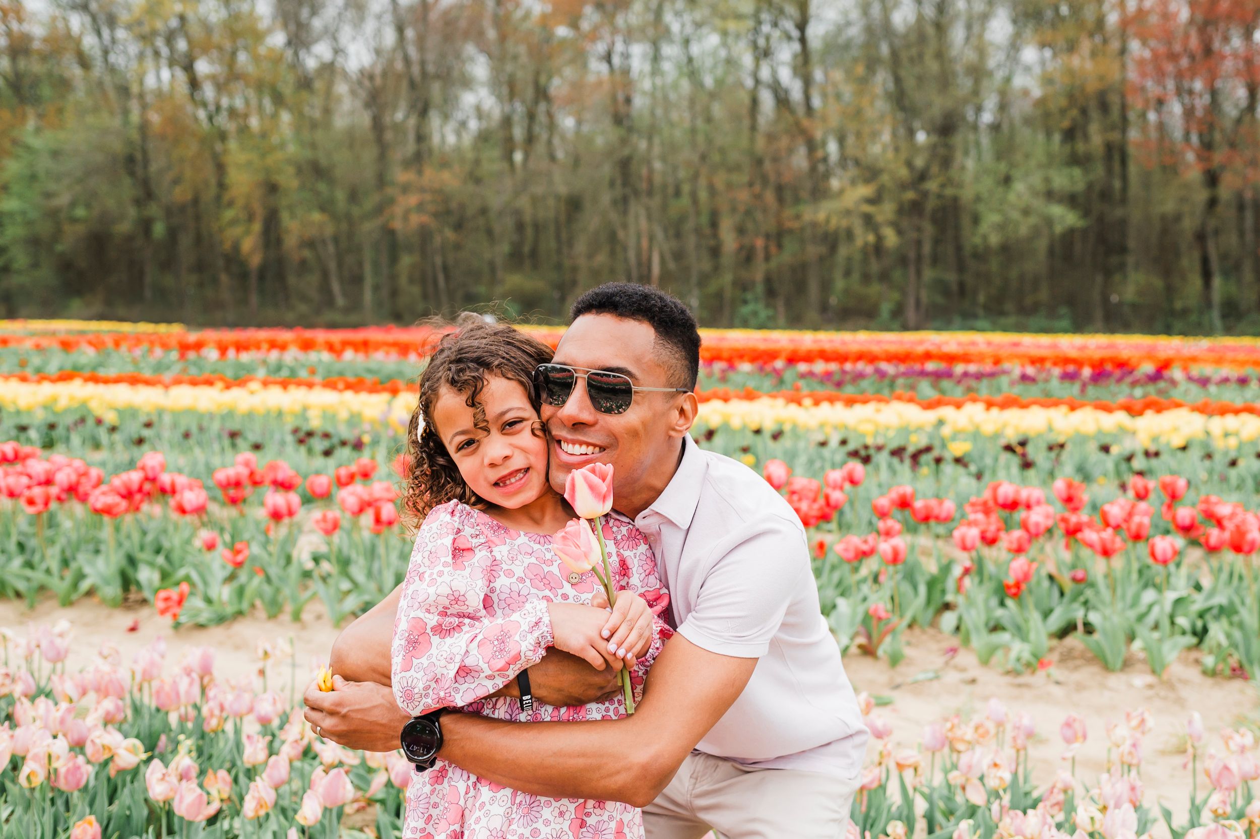 Group enjoying a springtime visit to colorful tulip fields in bloom on a sunny day.