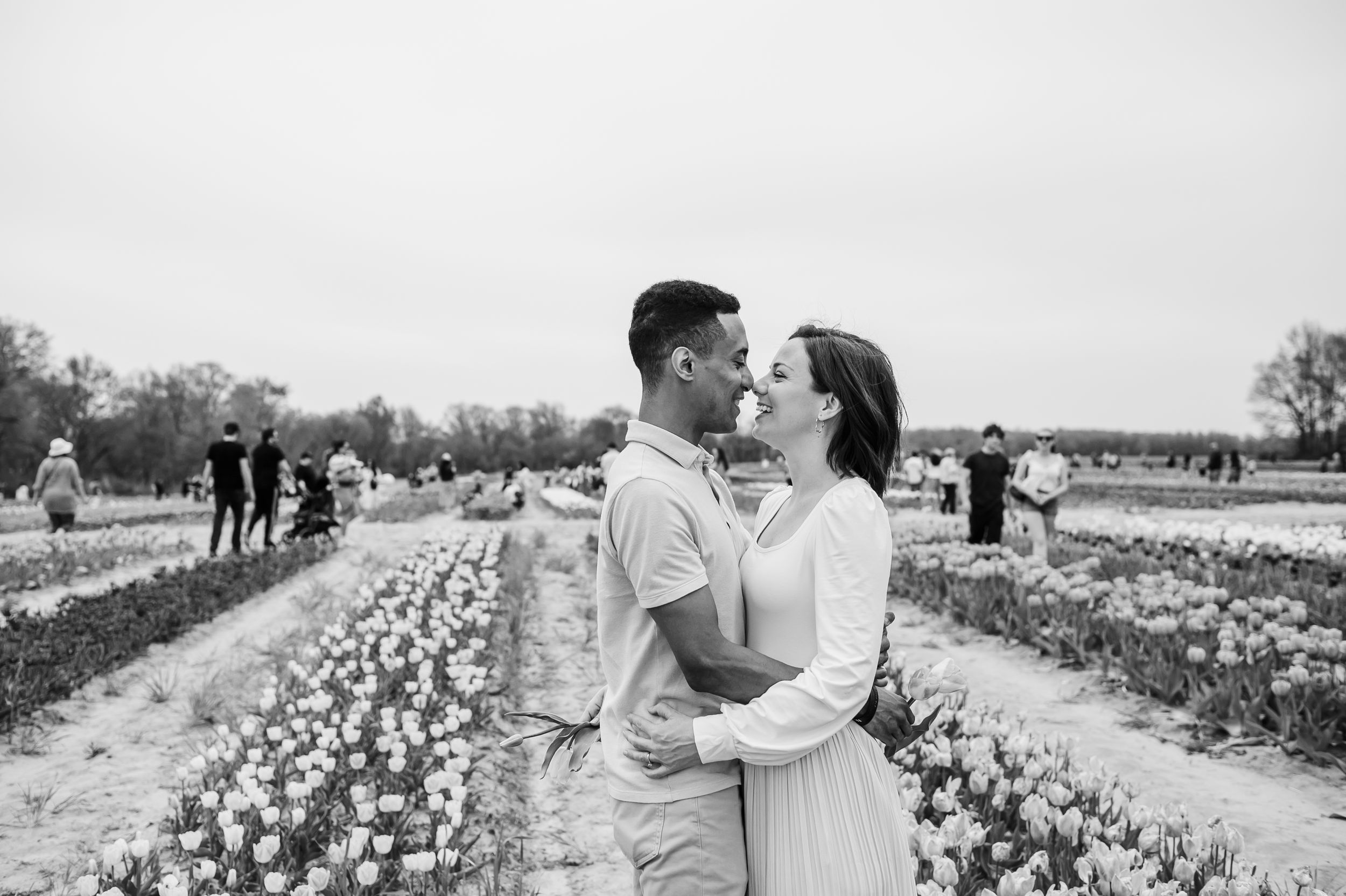 A romantic black and white portrait of a couple embracing in a blooming tulip garden.