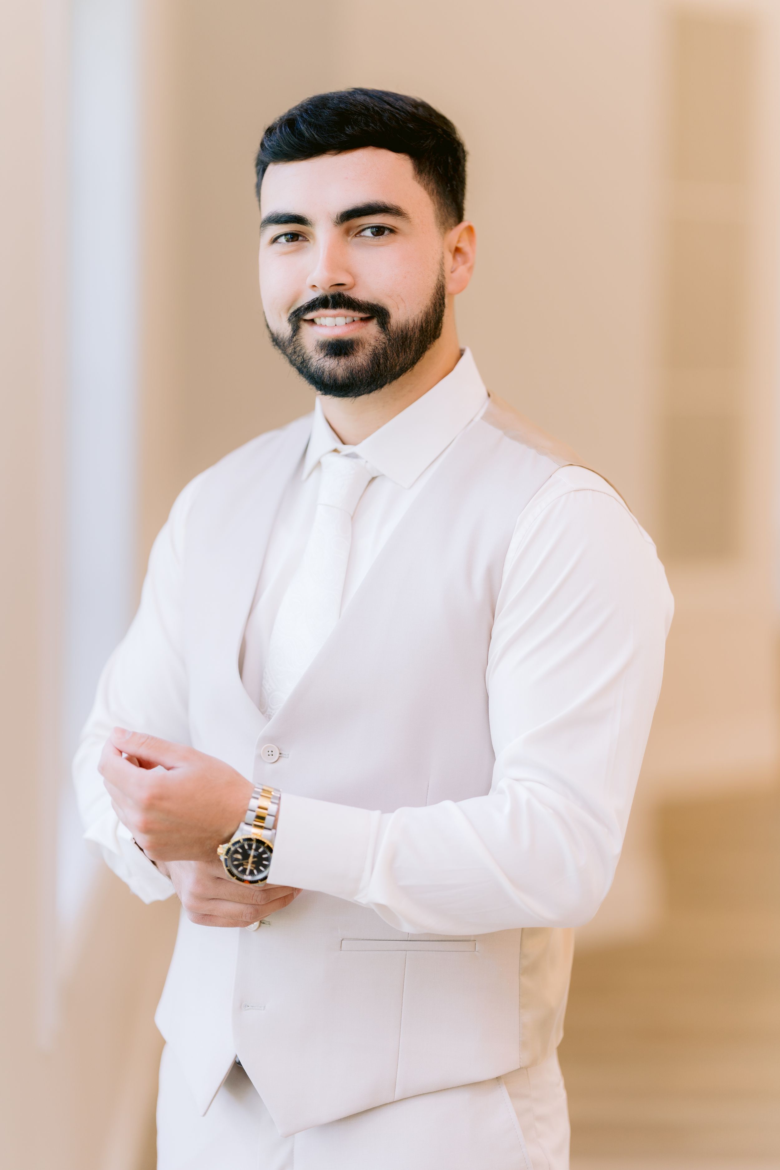 Professional portrait photo of someone in a white button-up shirt with arms crossed against a neutral background.