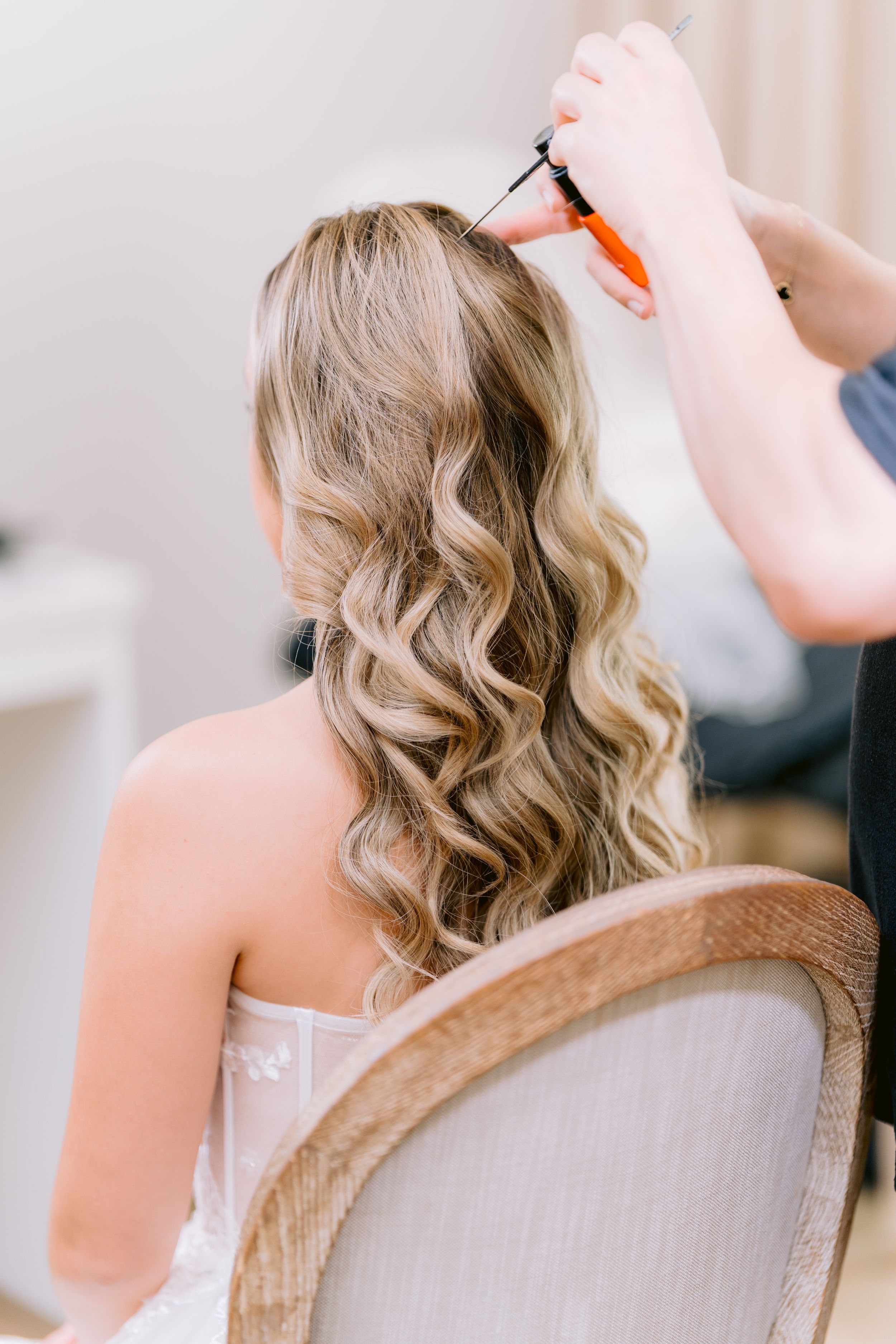 Professional hairstylist creating elegant curls with a styling tool for a special occasion.