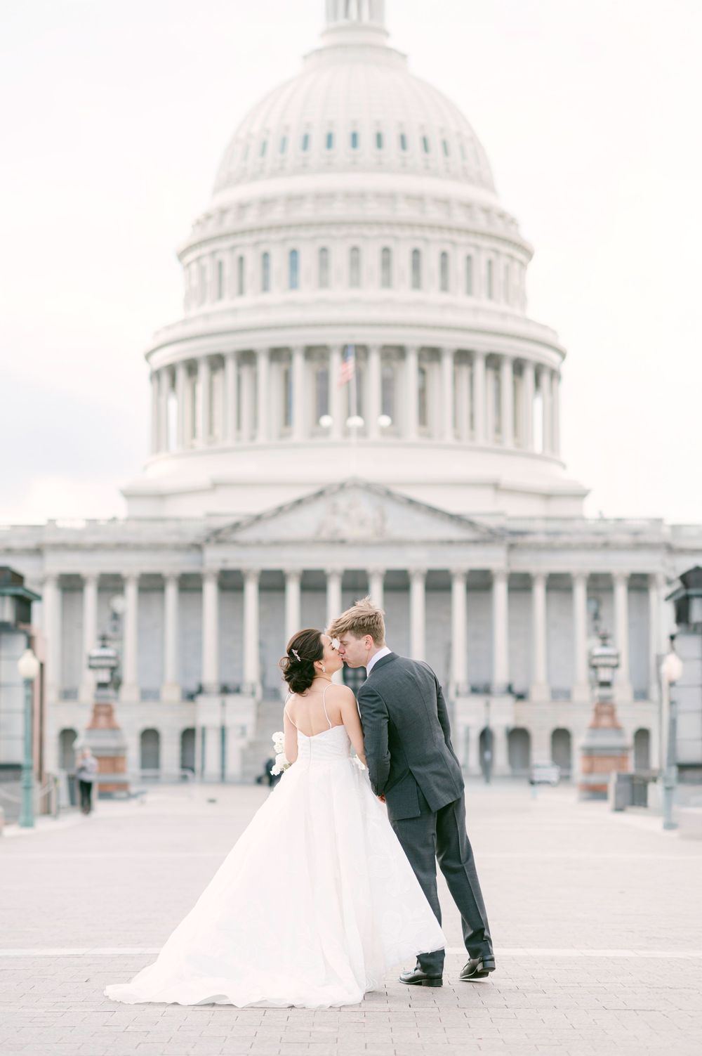 Romantic wedding photo in front of the US Capitol building on an overcast day.