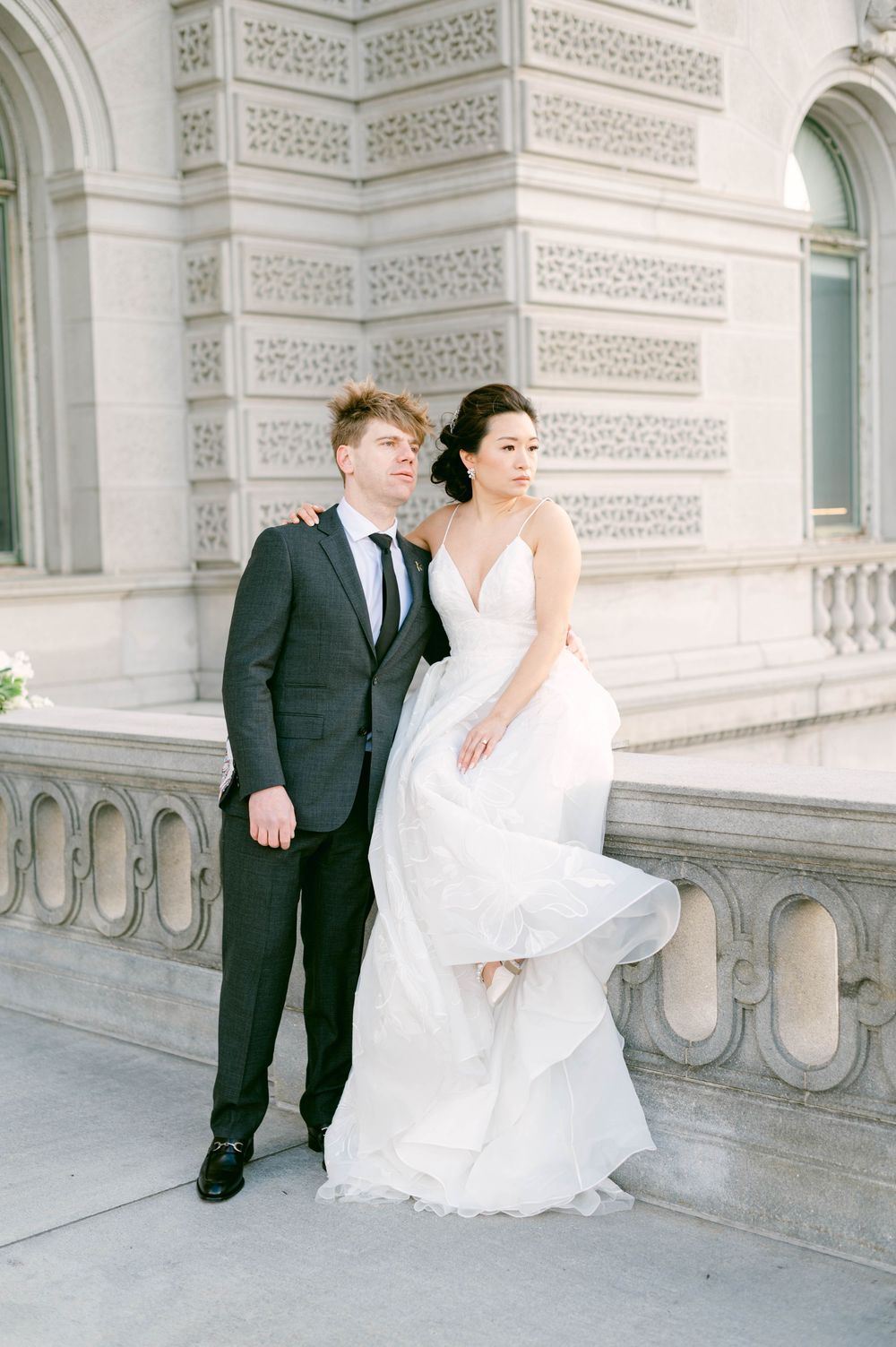 Elegant wedding portrait against classic architectural details with ornate stonework.