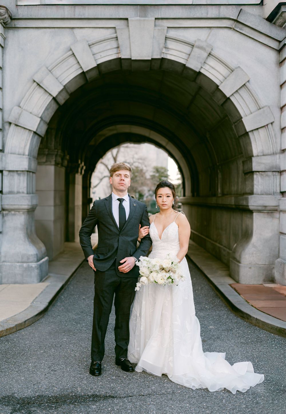 Newlywed couple standing in a stone archway during their wedding photoshoot.