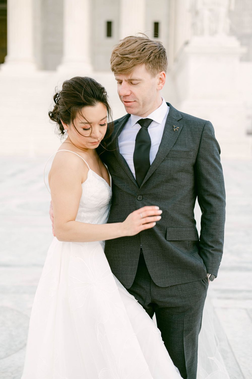 Intimate wedding portrait of couple against white classical architecture.