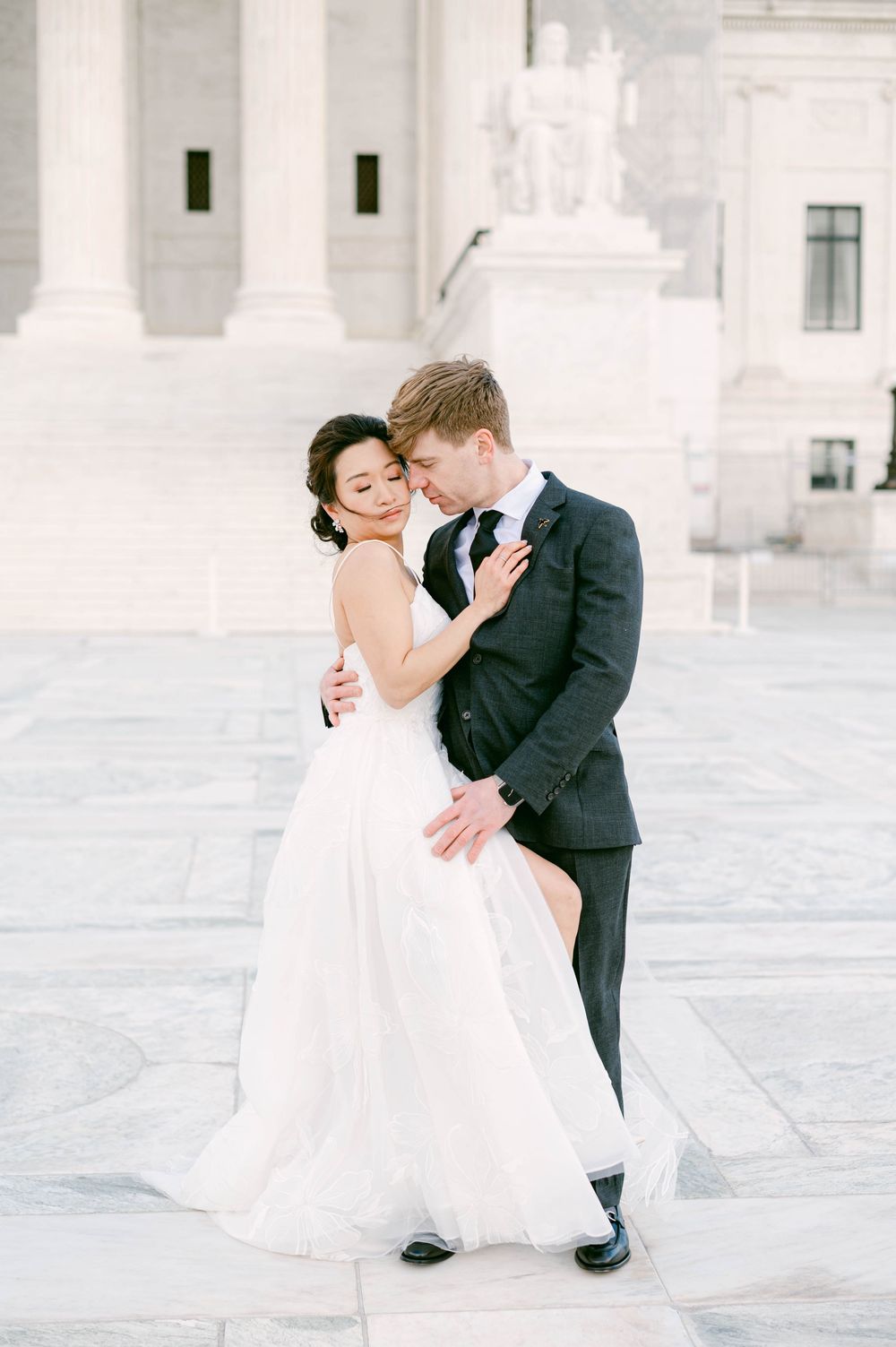 Romantic wedding portrait of couple embracing on marble steps.