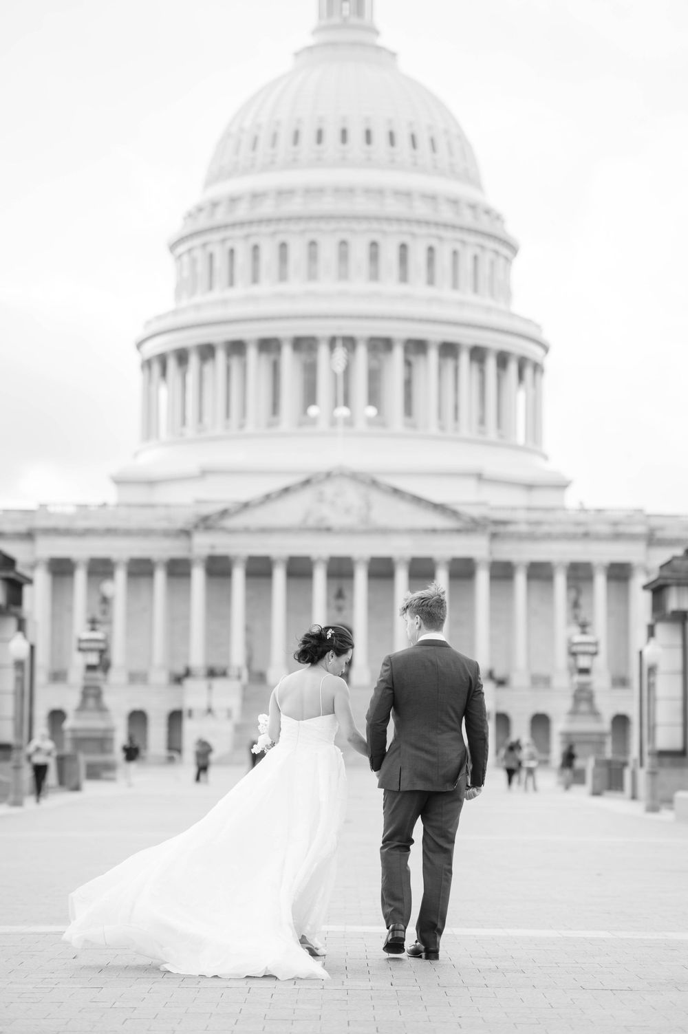 Black and white photo of newlyweds walking towards US Capitol building.