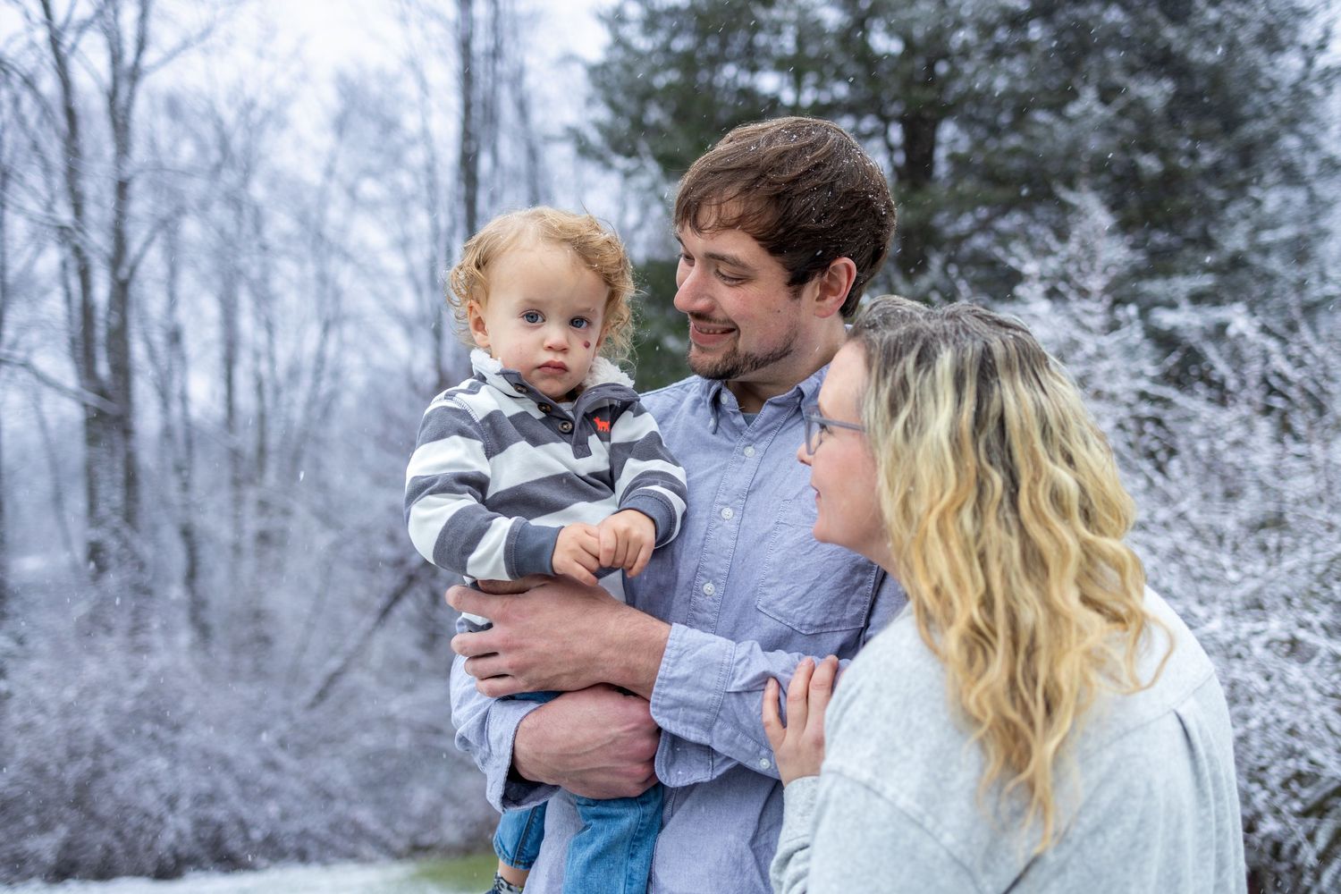 A family enjoys a peaceful winter moment together in a snowy forest landscape setting.
