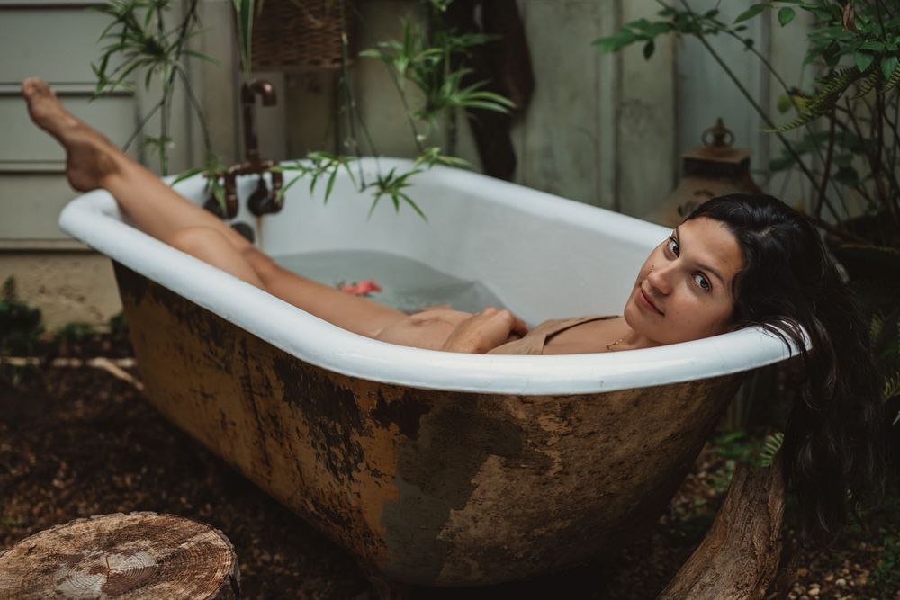 woman lounges in backyard bathtub caressing her pregnant belly