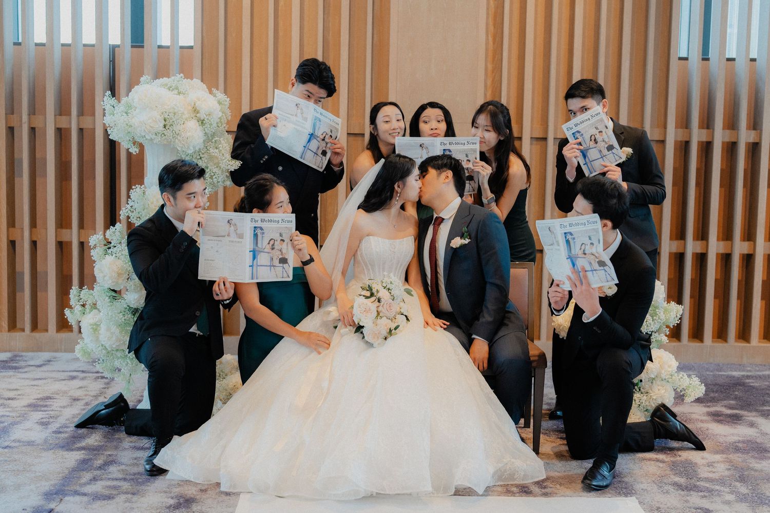 Wedding party poses with newspapers during a fun photo session with modern decor.