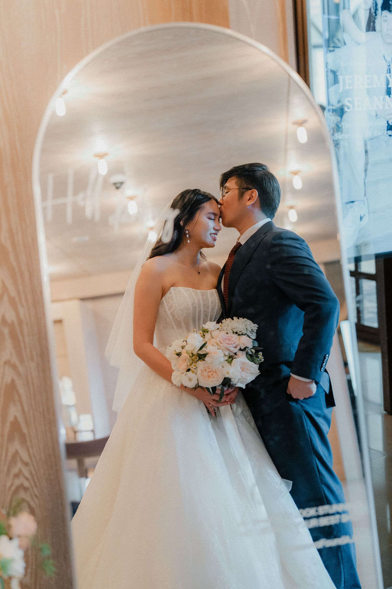 Wedding couple sharing an intimate moment in front of arched windows.
