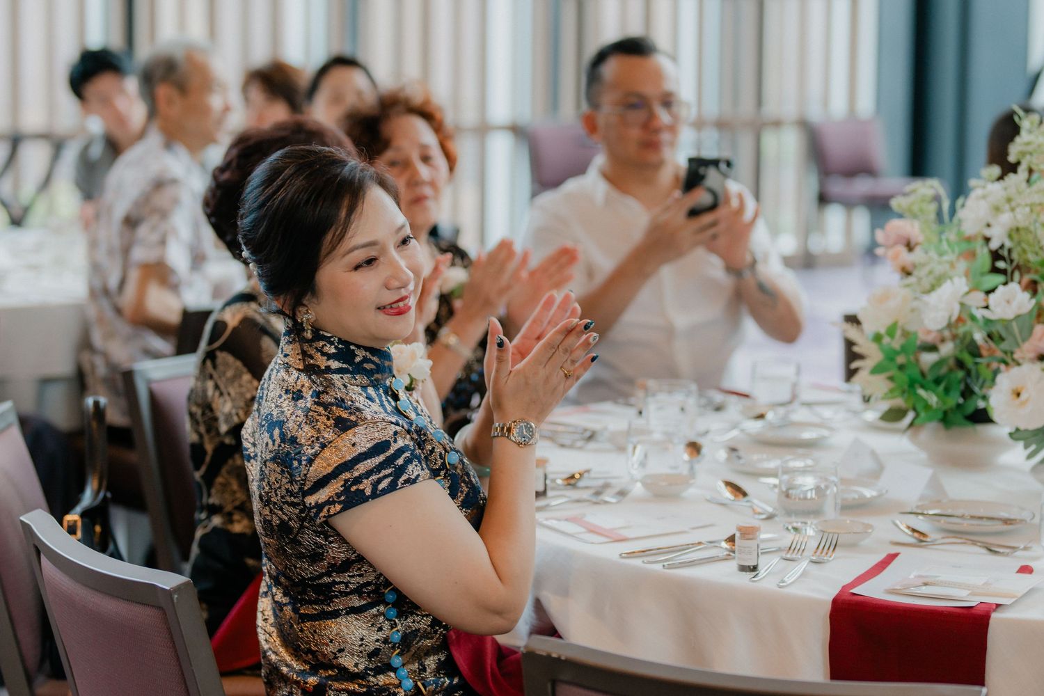 Guests enjoy a festive celebration at an elegant wedding reception with white tablecloths and floral centerpieces.