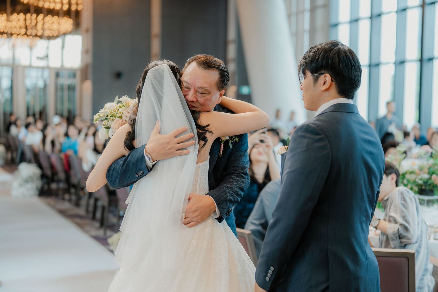 Touching moment during wedding ceremony as family members embrace the bride.
