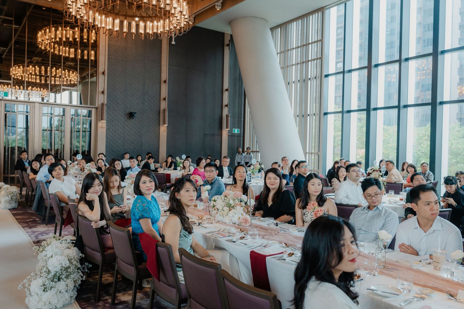 Spacious wedding venue with floor-to-ceiling windows and white-clothed tables set for reception dining.