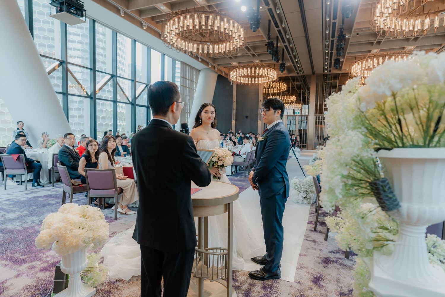 Elegant wedding ceremony setup with crystal chandeliers and white floral arrangements.