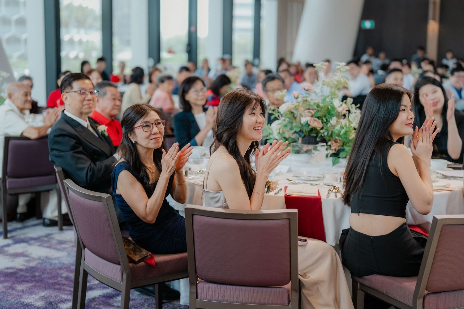 Wedding guests seated in rows of chairs enjoying the reception entertainment.