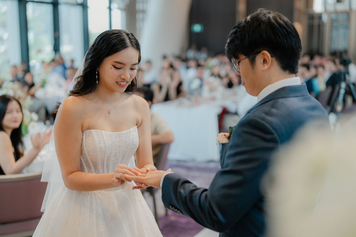 Elegant wedding celebration in modern venue with couple exchanging rings during ceremony.