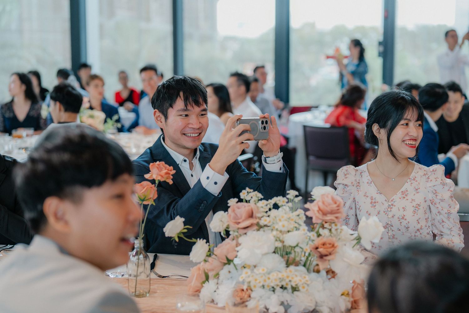 A wedding banquet reception with guests seated at decorated tables enjoying a celebratory meal together.