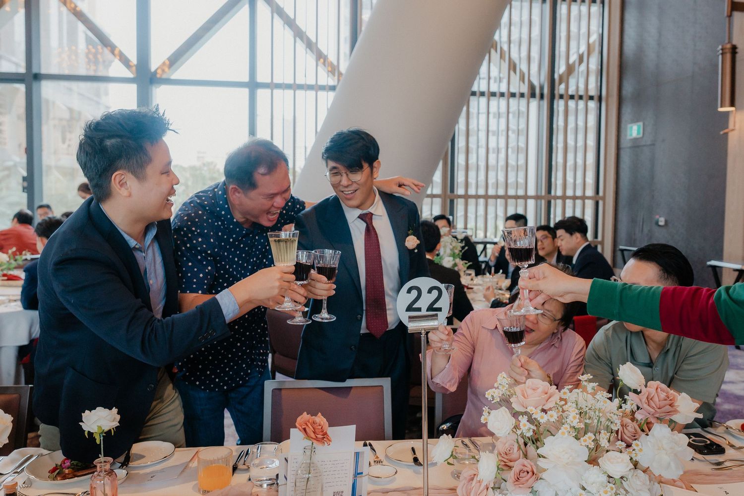 Wedding guests socializing and toasting at a decorated reception table with table number 22.