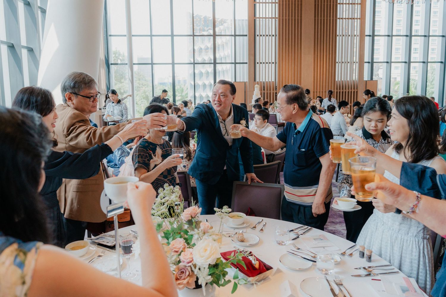Wedding celebration in a contemporary venue with natural lighting and guests seated at long tables.