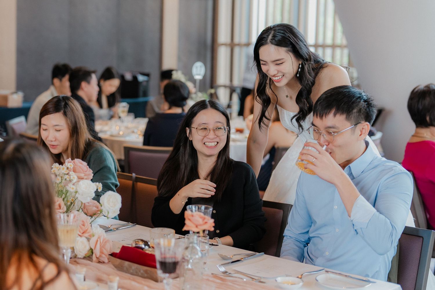 Wedding reception guests share joyful moments around elegantly decorated dining tables.