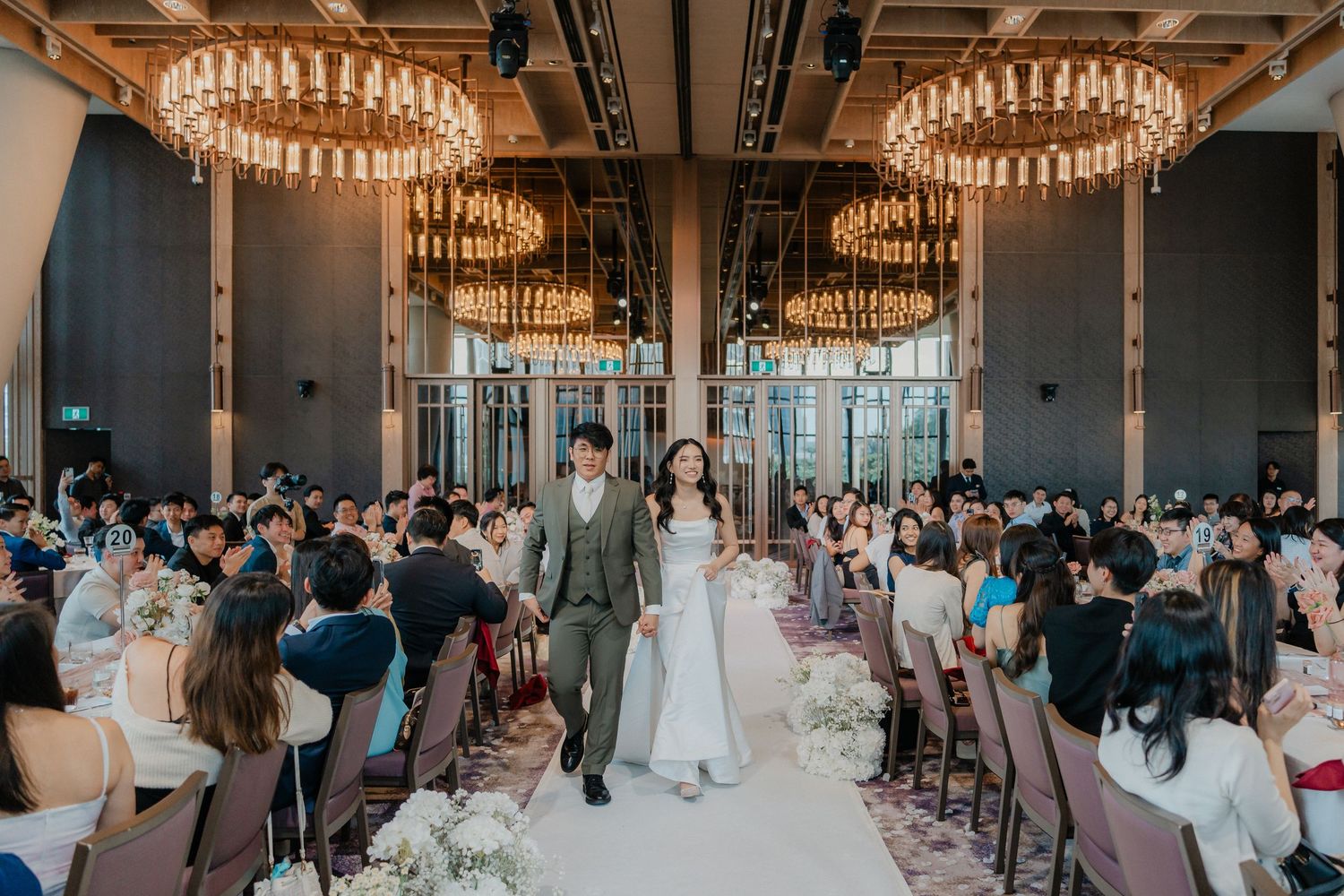 Wedding reception venue with large circular chandeliers and guests gathered for the celebration.