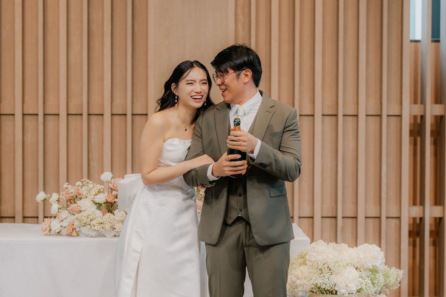 A couple shares an intimate moment while enjoying drinks at their wedding reception.