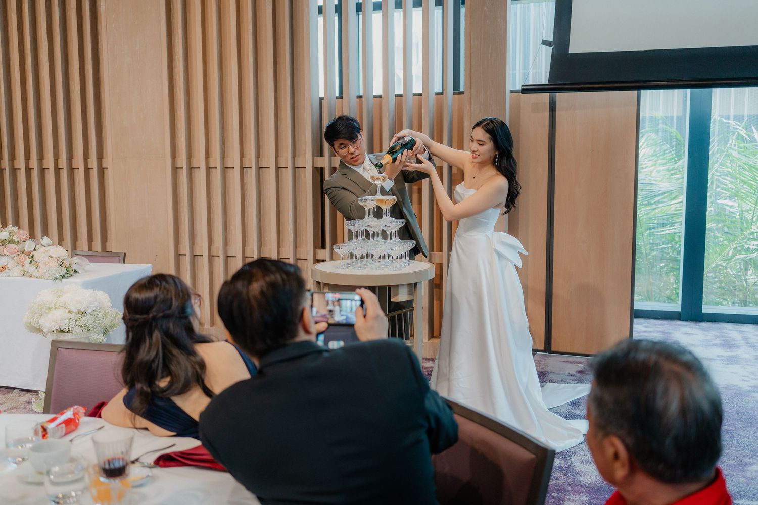 Celebratory champagne tower pouring at an elegant wedding reception.