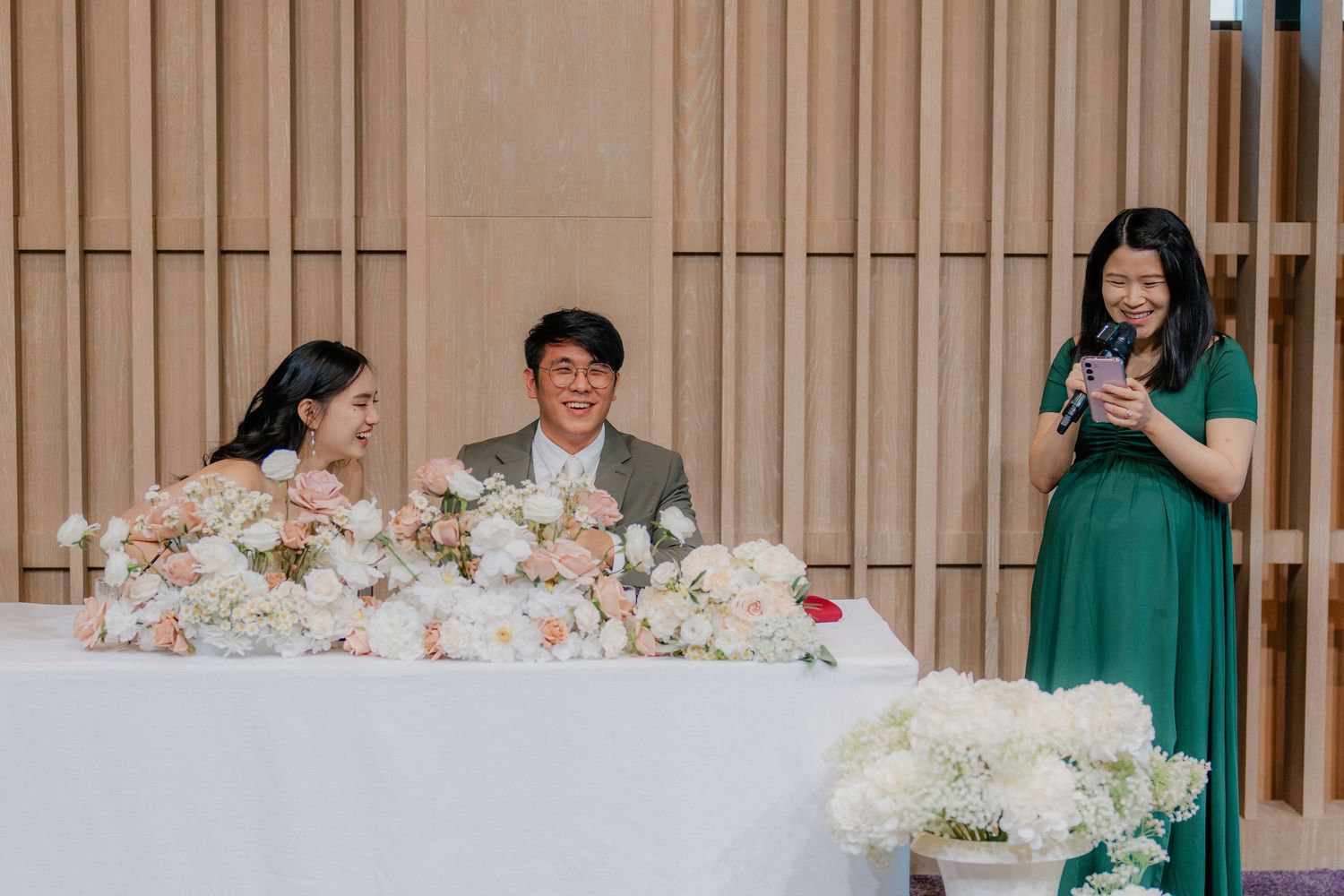 A celebratory moment at an elegant wedding reception with floral decorations on the head table.