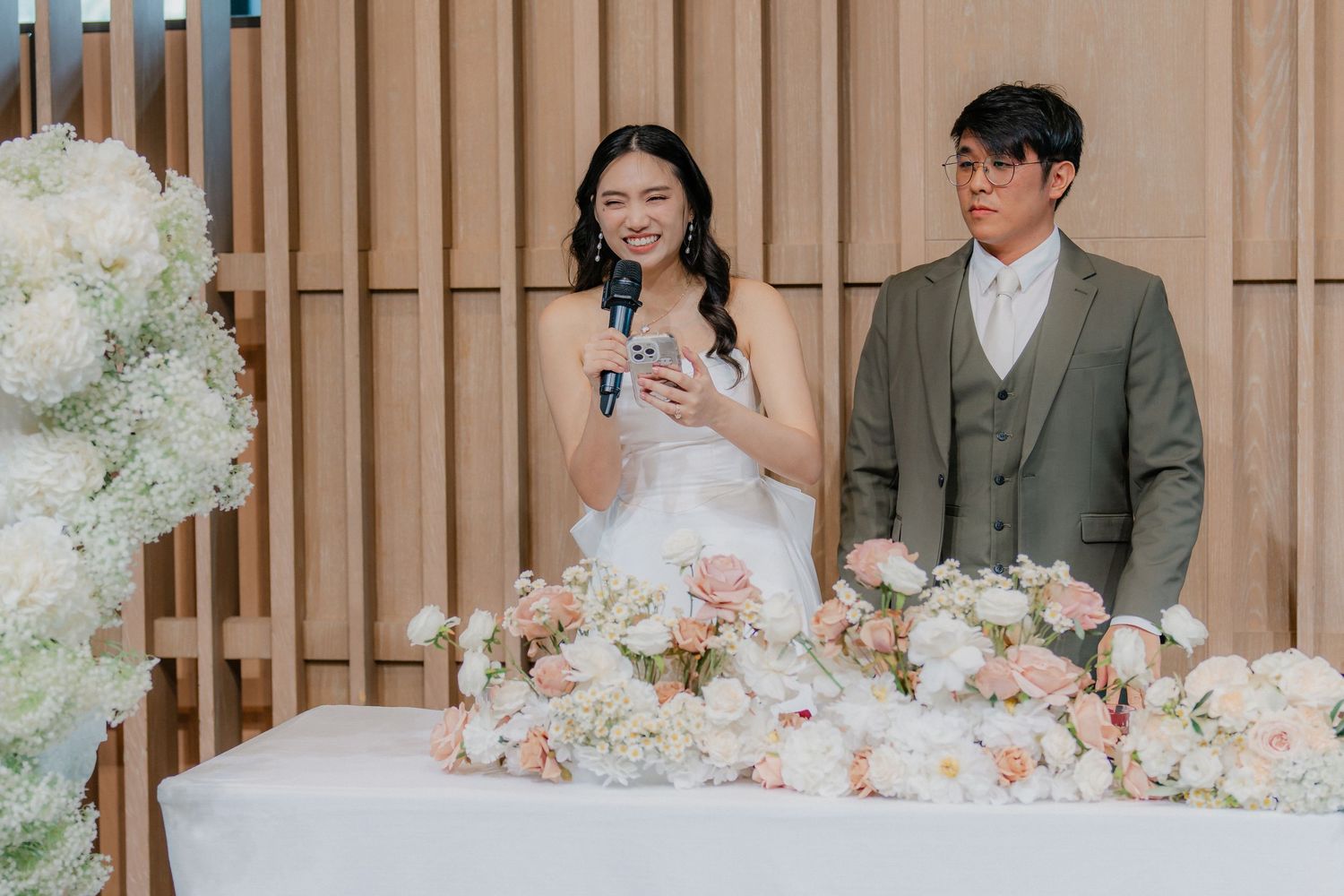 Wedding party celebrates at a modern venue decorated with pink and white floral centerpieces.
