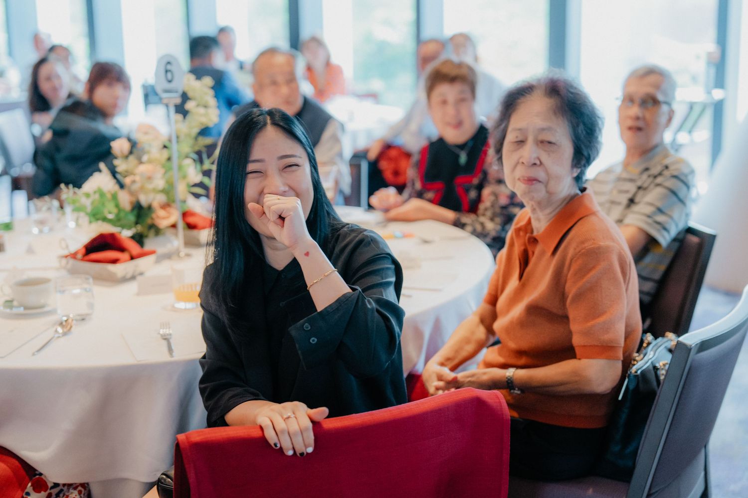 Wedding reception guests enjoying a meal at round tables decorated with centerpieces.