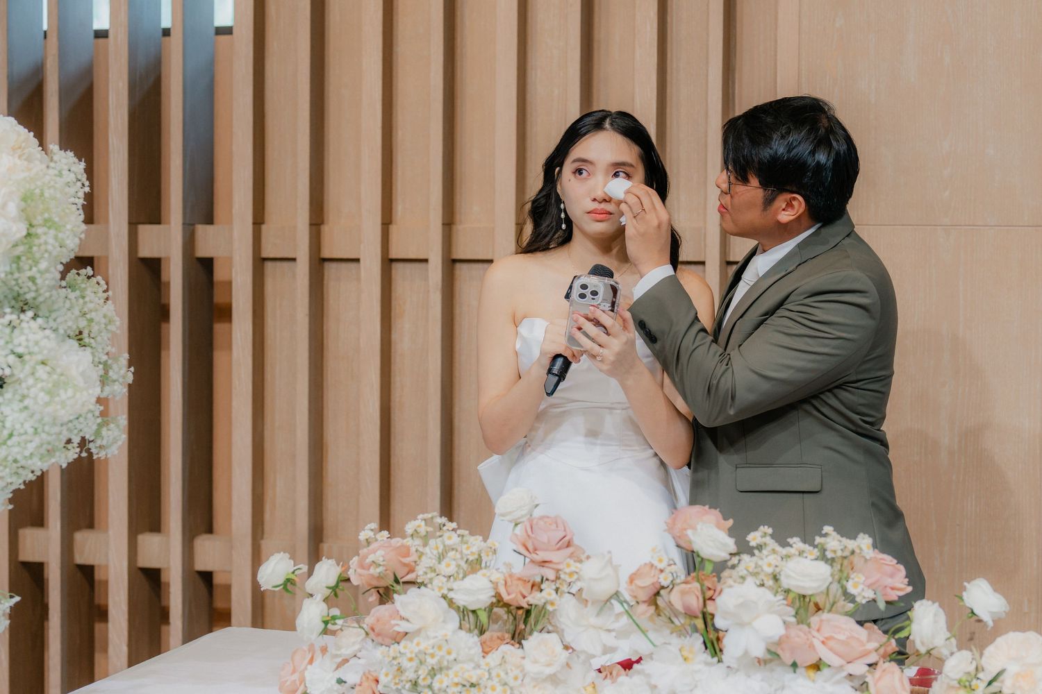 Wedding celebration with floral decorations and guests at elegant indoor venue.