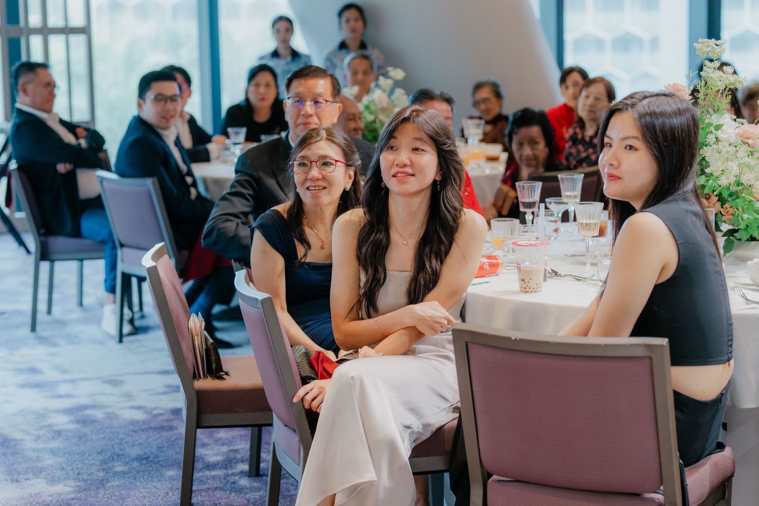 Guests seated at dining tables during an elegant indoor social event with blue-tinted lighting and modern decor.