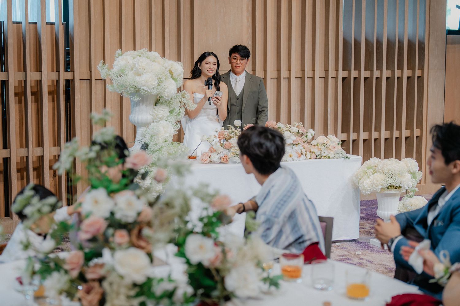 Elegant wedding reception table decorated with lush white and pink floral arrangements and fine dining settings.