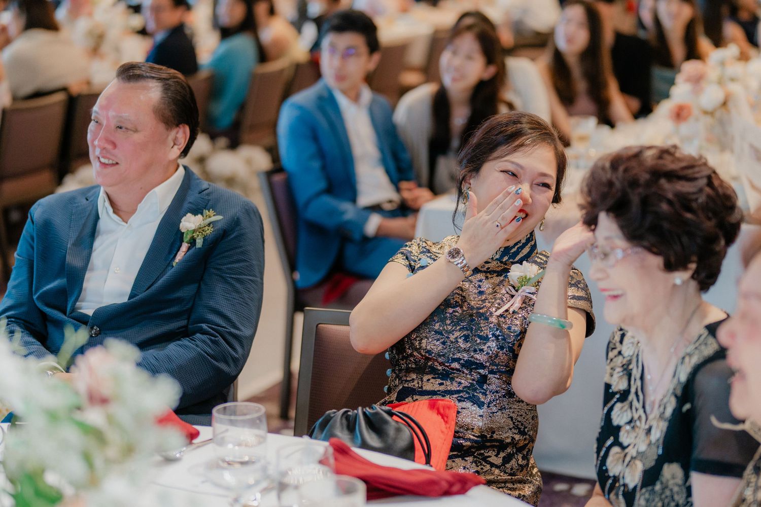Wedding reception guests seated at decorated tables during an emotional moment.
