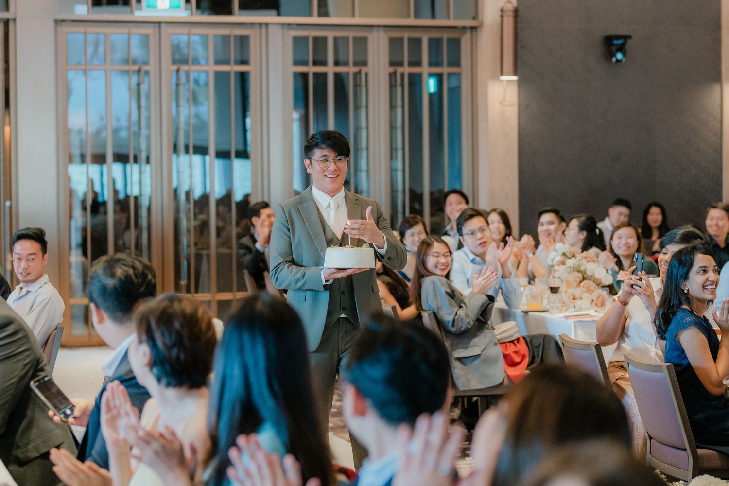 Wedding guests celebrate during a lively reception in an elegant banquet hall.