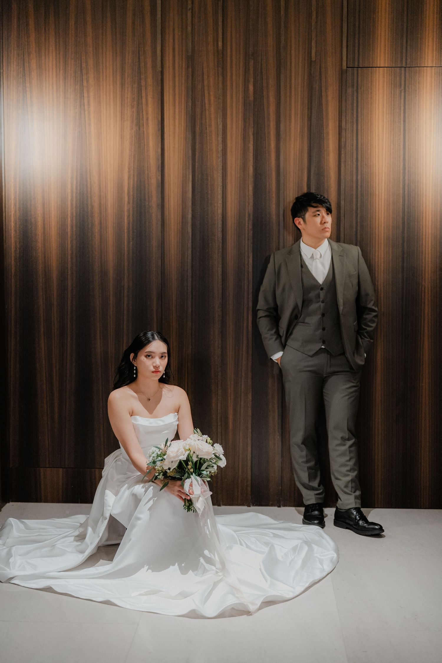 A couple poses elegantly against a wooden wall backdrop for their wedding portrait.