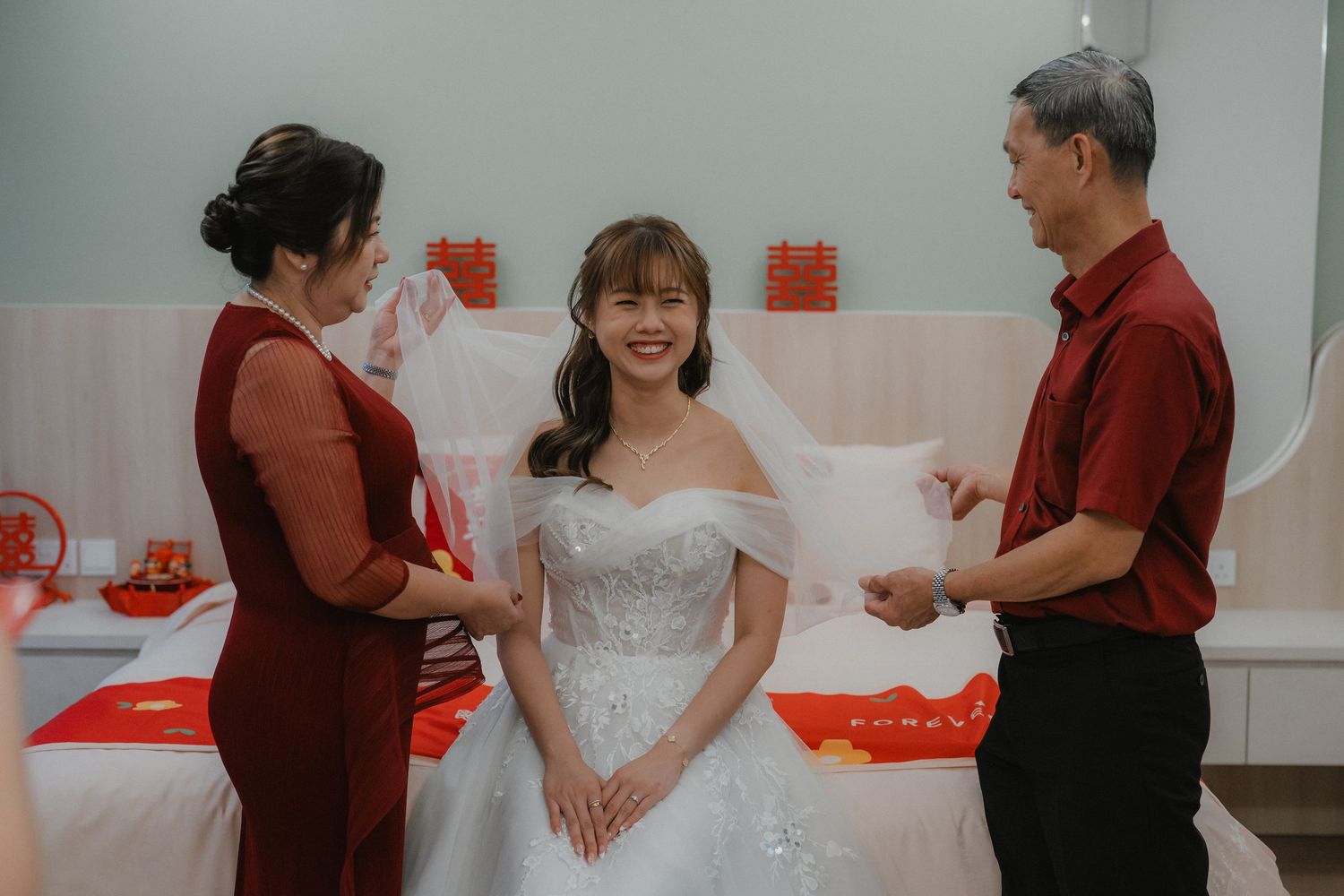 Wedding couple and guests participate in traditional Chinese tea ceremony with festive red decor.